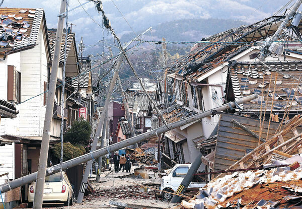 激しい揺れで倒壊した家屋や電柱＝２日午前７時３５分、輪島市河井町