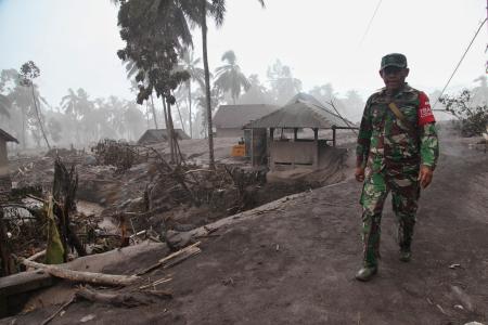 スメル山噴火で被災した家屋の近くを歩く当局者＝５日、インドネシア・ジャワ島東部（ゲッティ＝共同）