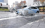 大雨で道路に水があふれ、水しぶきを上げて走る車両＝金沢市の香林坊交差点