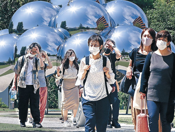 強い日差しの中を散策する観光客＝２５日午前１０時２０分、金沢２１世紀美術館