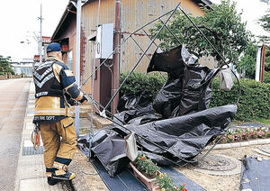 風で飛ばされたテントを撤去する消防隊員＝２４日正午、能美市福岡町