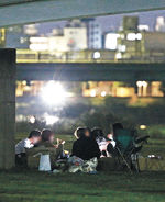 禁止区域でバーベキューをするグループ＝２３日午後１０時、金沢市の犀川緑地（画像の一部を加工）