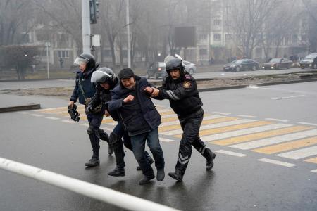 ５日、カザフスタン・アルマトイで、警察官に拘束される抗議デモ参加者（右から２人目）（ＡＰ＝共同）
