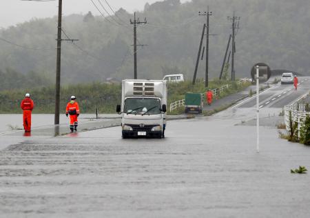 大雨の影響を受け水がたまった道路で動けなくなった車＝１０日午後０時４４分、鹿児島県伊佐市